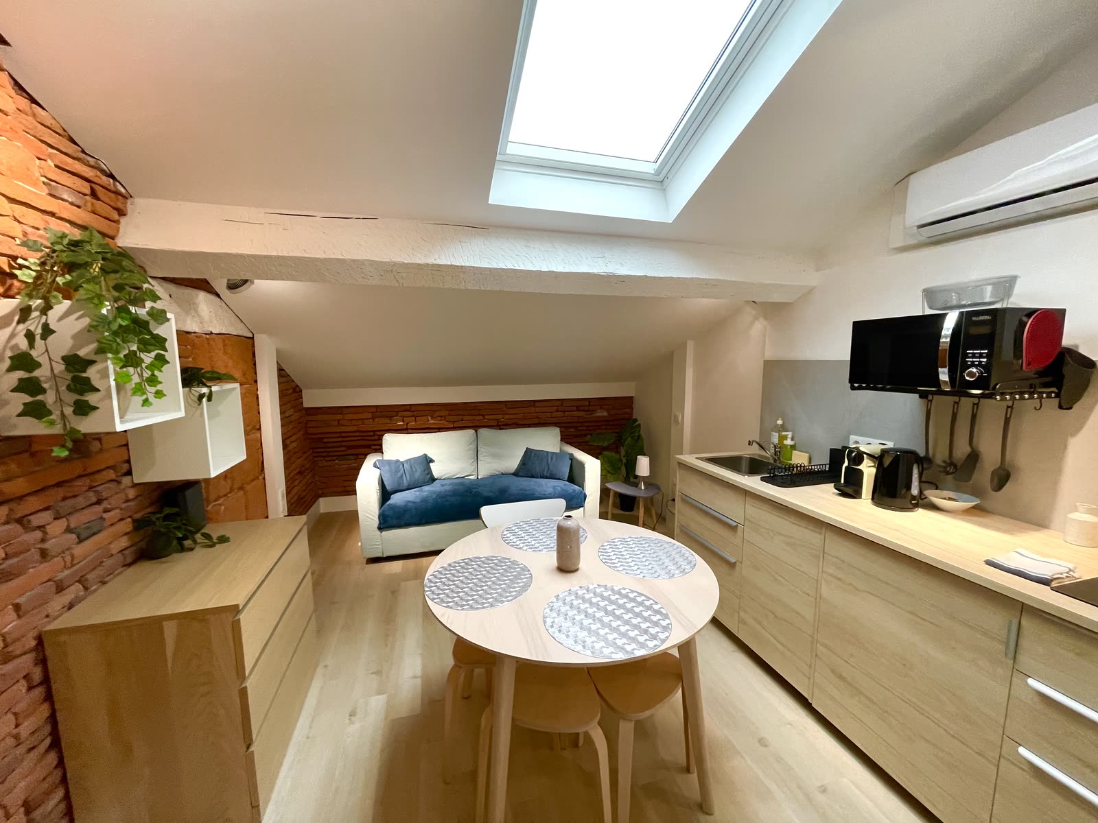 Pièce de vie d'un appartement du quartier du Capitole géré par Takeys : briques apparentes, cuisine ouverte et mezzanine
