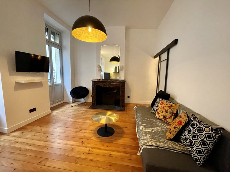 Salon d'un appartement du quartier des Carmes géré par Takeys : parquet ancien et cheminée
