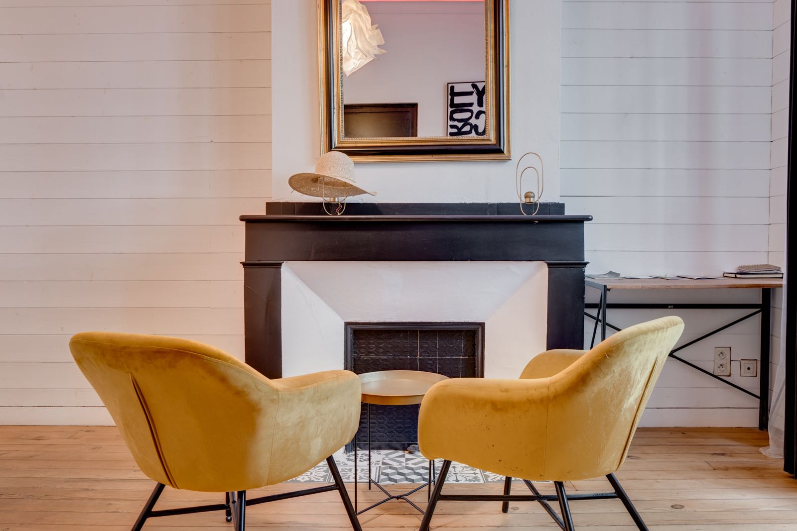 Séjour d'un appartement toulousain géré par Takeys : cheminée ancienne, fauteuils en velours et parquet clair
